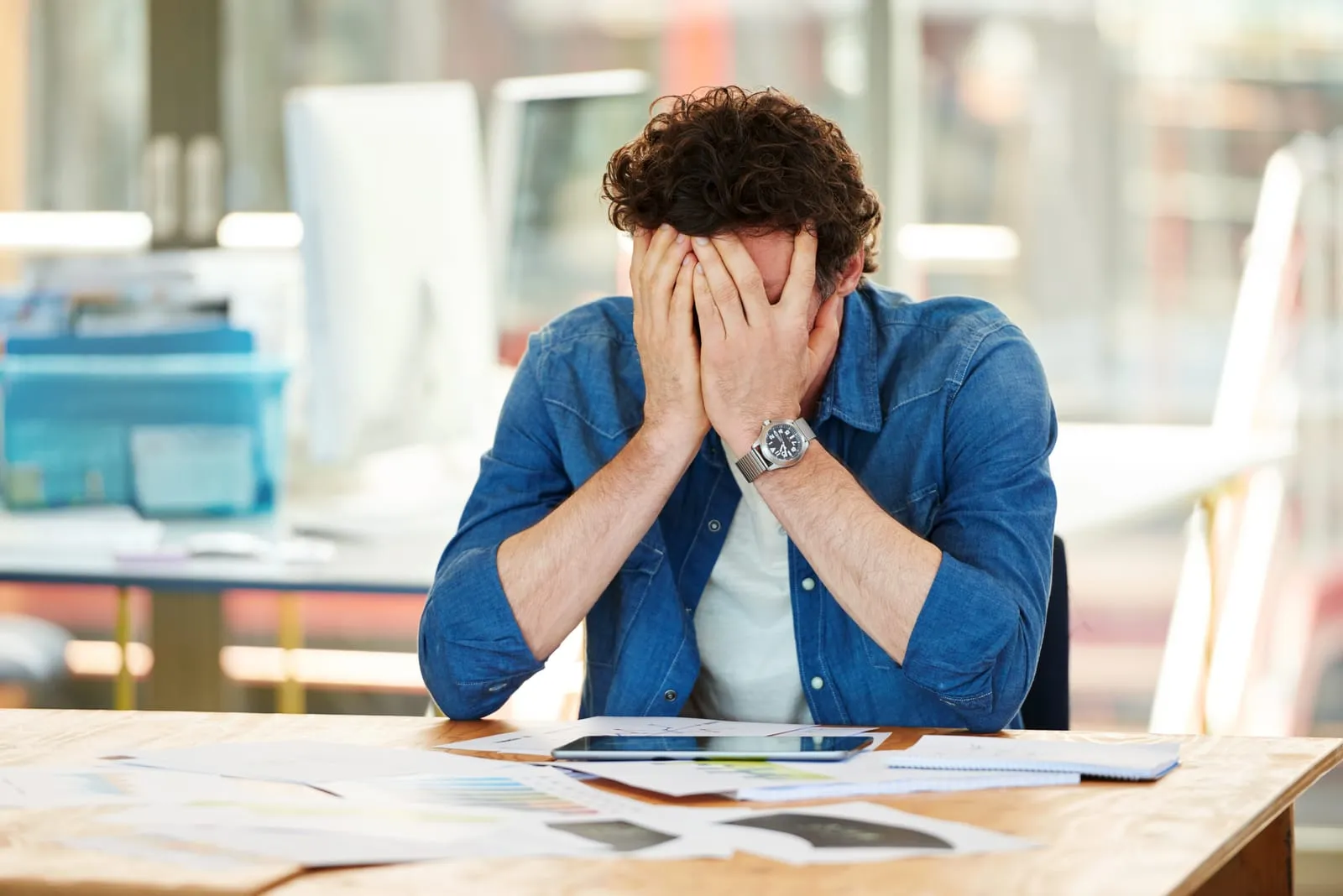 Person surrounded by paper invoices at a cluttered desk